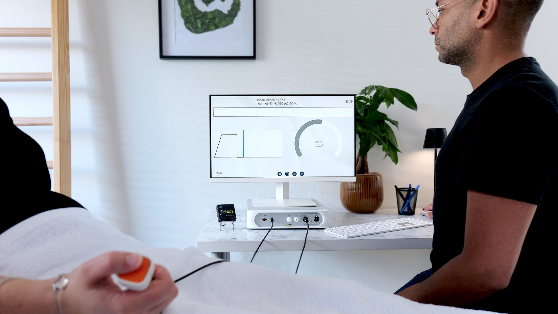 Une patiente réalise un exercice avec l'appareil BioStim, accompagné de son kinésithérapeute.