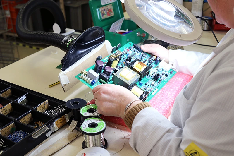 Vérification minutieuse d'une carte électronique à la loupe chez Mazet Santé, garantie de qualité et de précision pour nos appareils médicaux et esthétiques